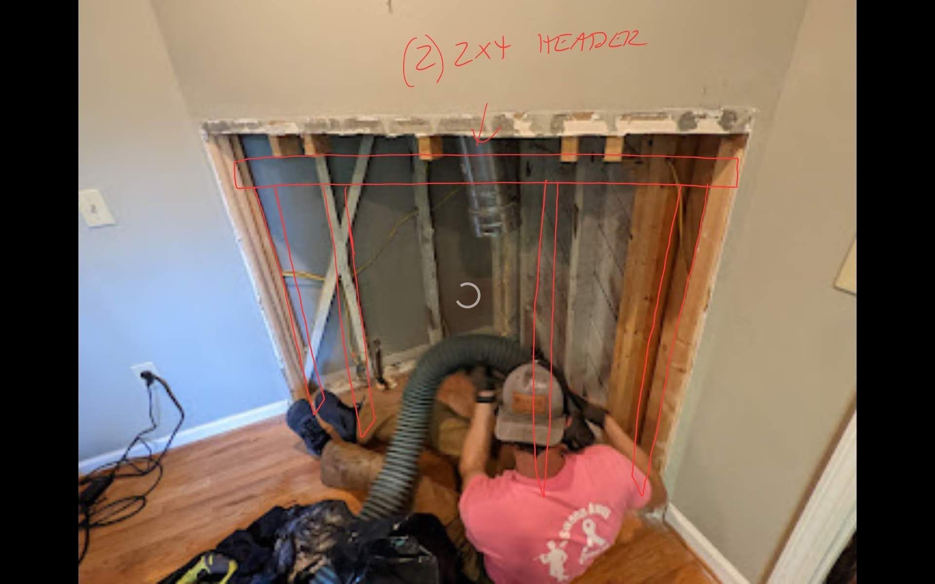 A man is using a vacuum cleaner to remove water from a wall.