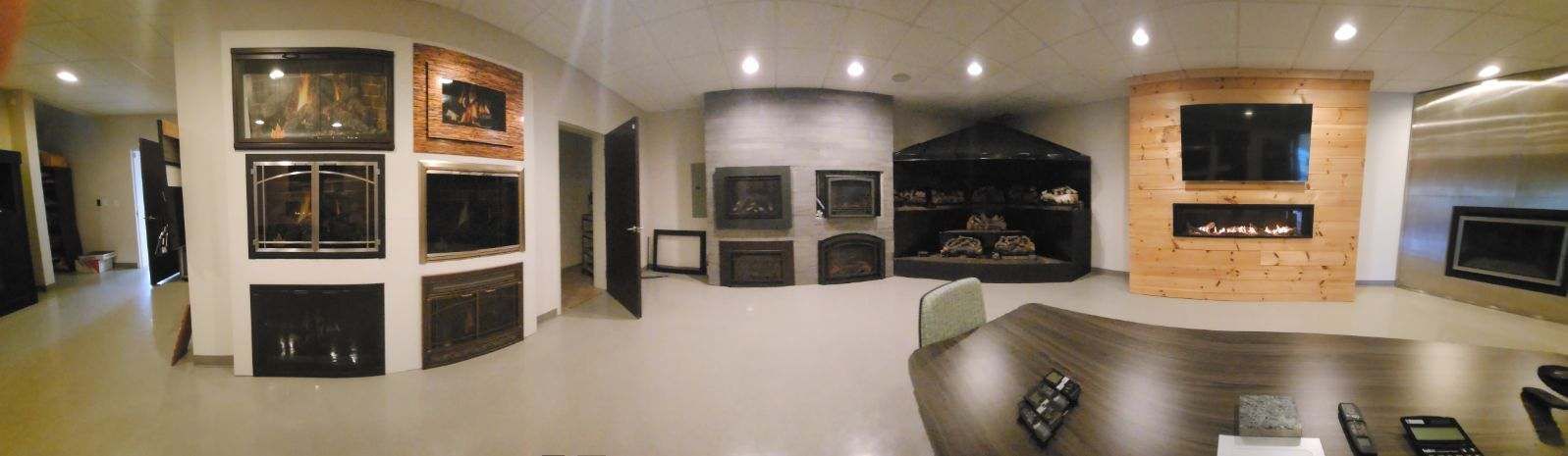 a large room with a lot of televisions on the wall and a fireplace .