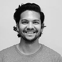 A man with a beard is smiling in a black and white photo.