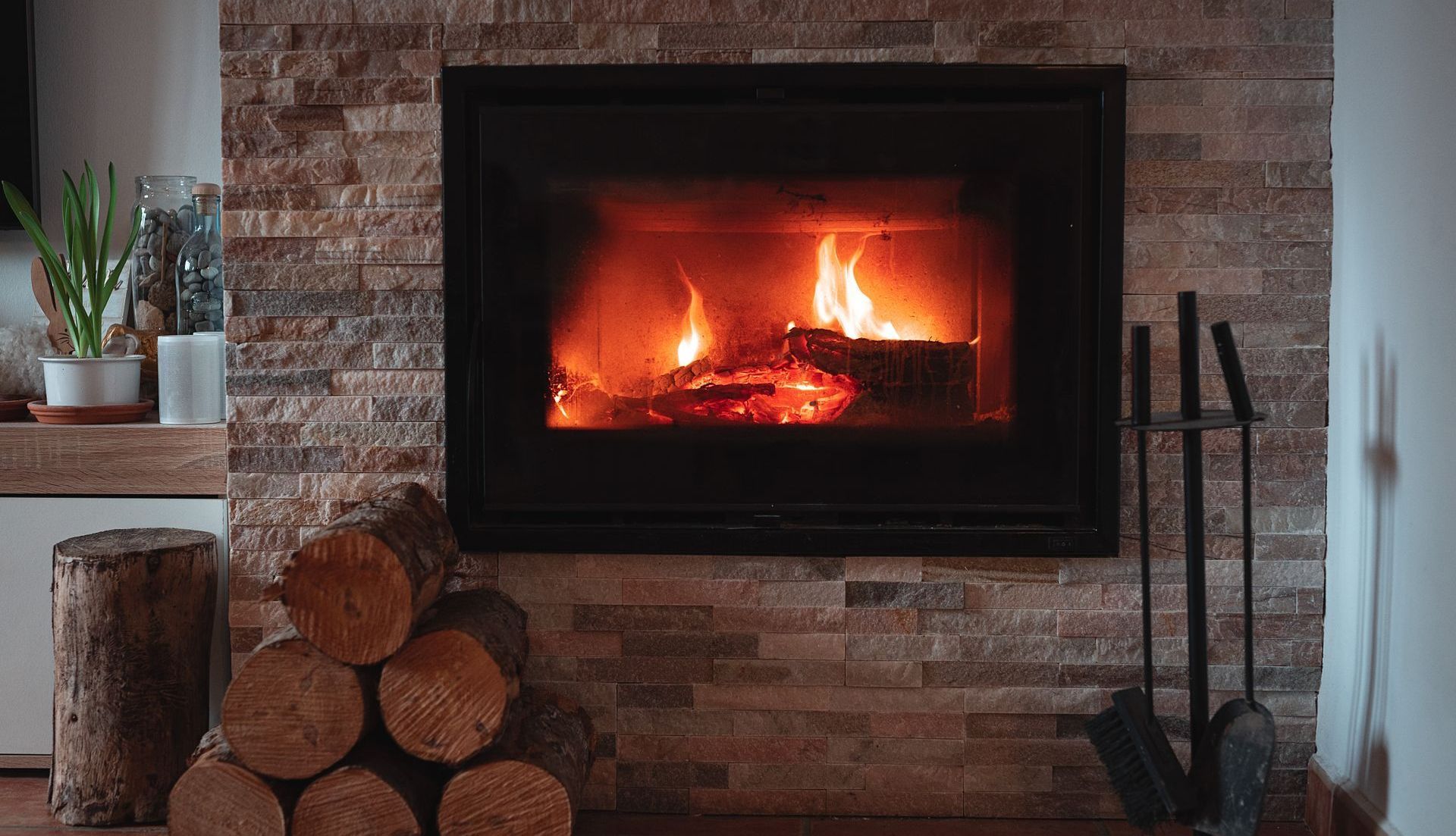 A fireplace with a pile of logs in front of it.