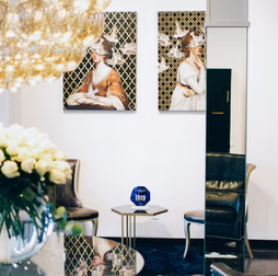 Elegant interior with art, chairs, and table. Mirrors reflect objects.