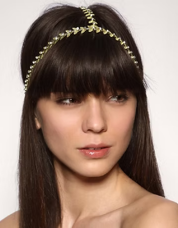 Woman with long dark hair, wearing a gold headpiece with jewels.