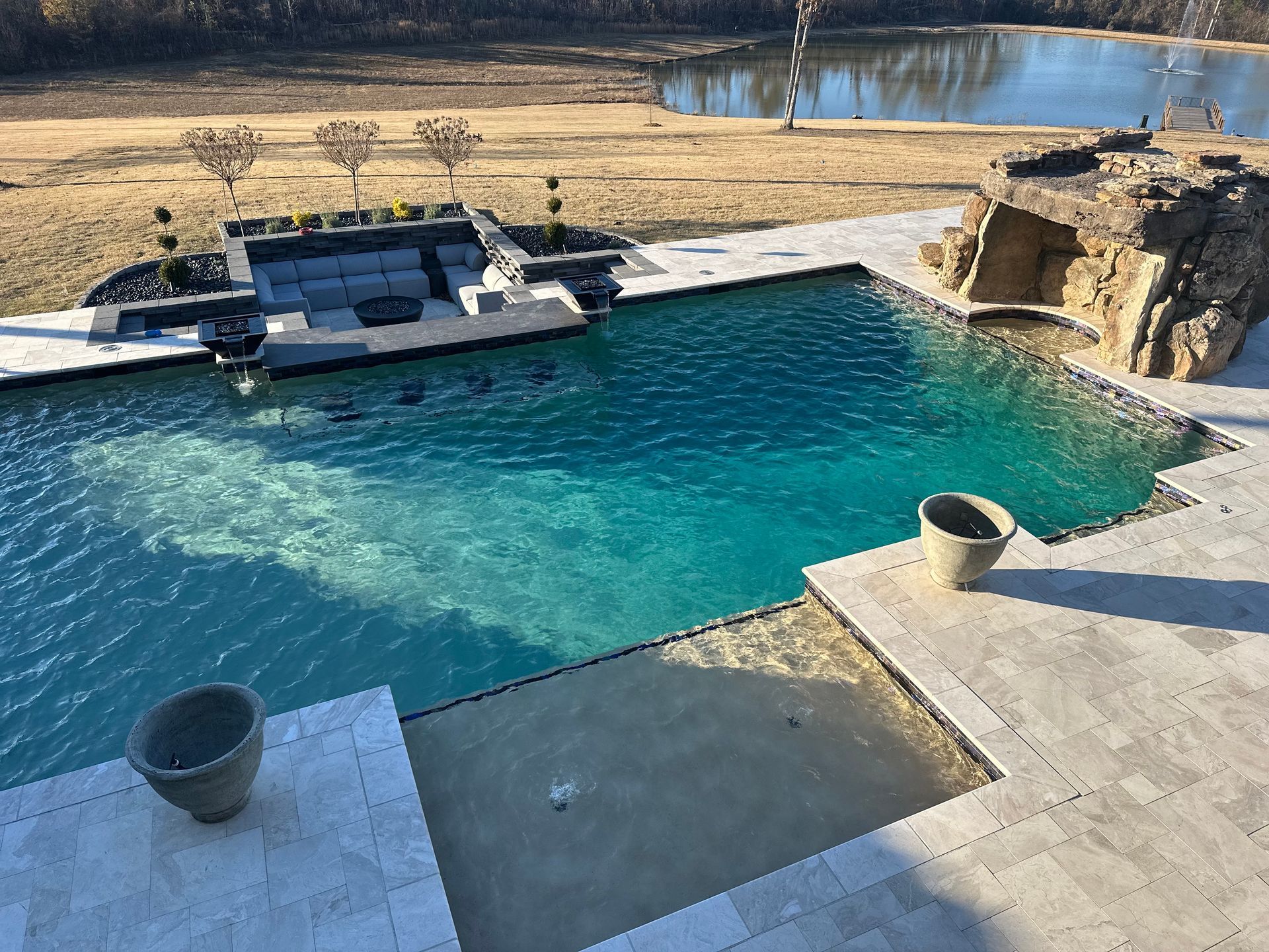 Luxurious outdoor pool with seating area, rock feature, and scenic background.