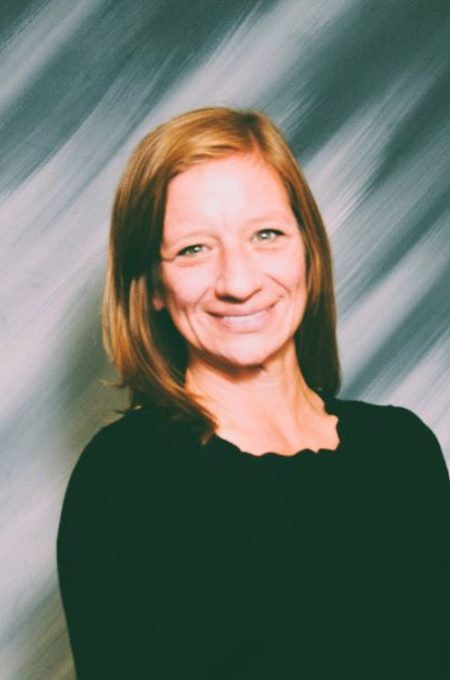 Smiling woman in a black top against a gray streaked studio background