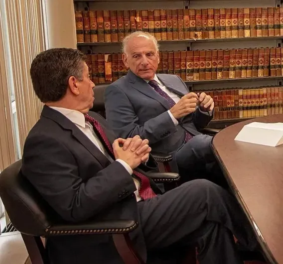 Two men in suits and ties are sitting at a table talking