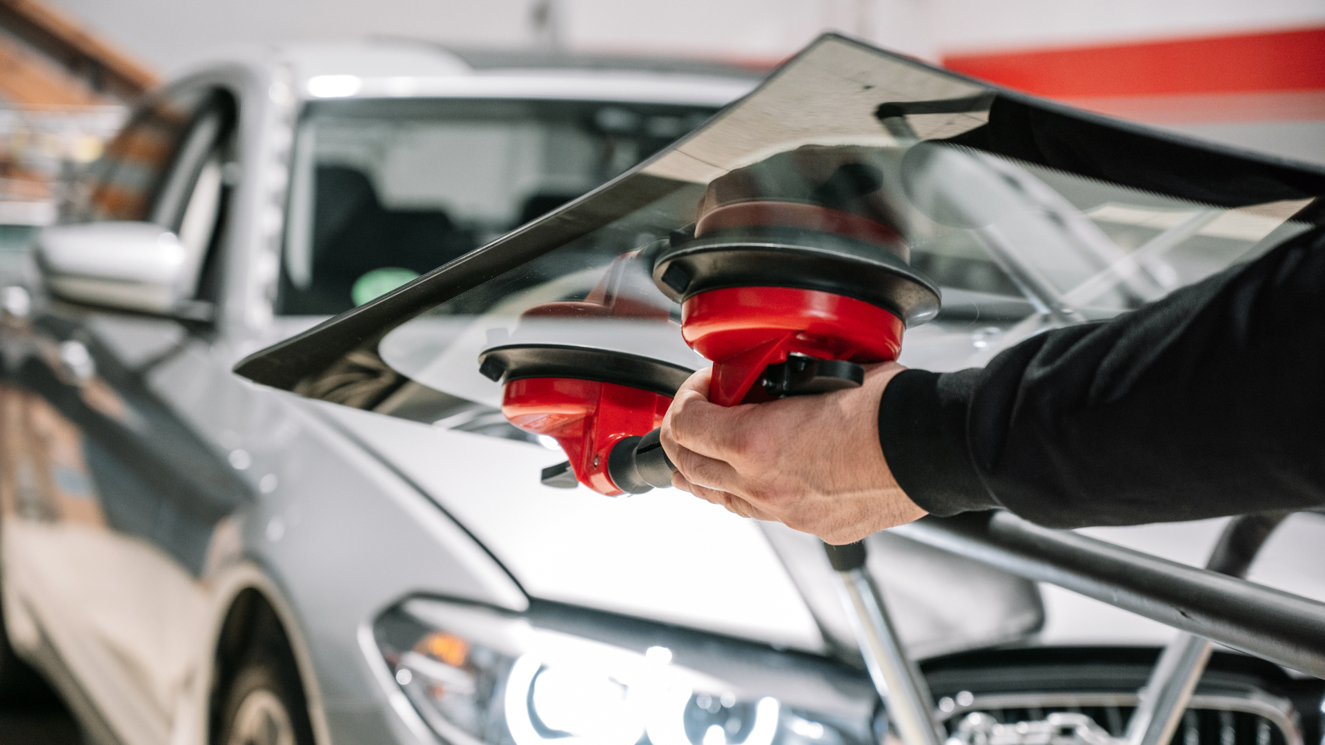 A man is installing a windshield on a car.