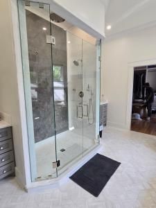 A bathroom with a walk in shower and a rug on the floor.