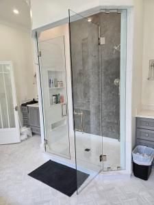 A bathroom with a walk in shower and a trash can.