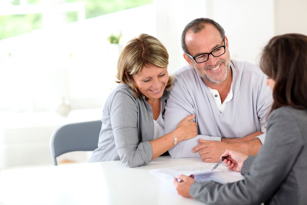 A Man and a Woman Are Sitting at a Table Talking to a Woman — All About Conveyancing Taree In Forster, NSW