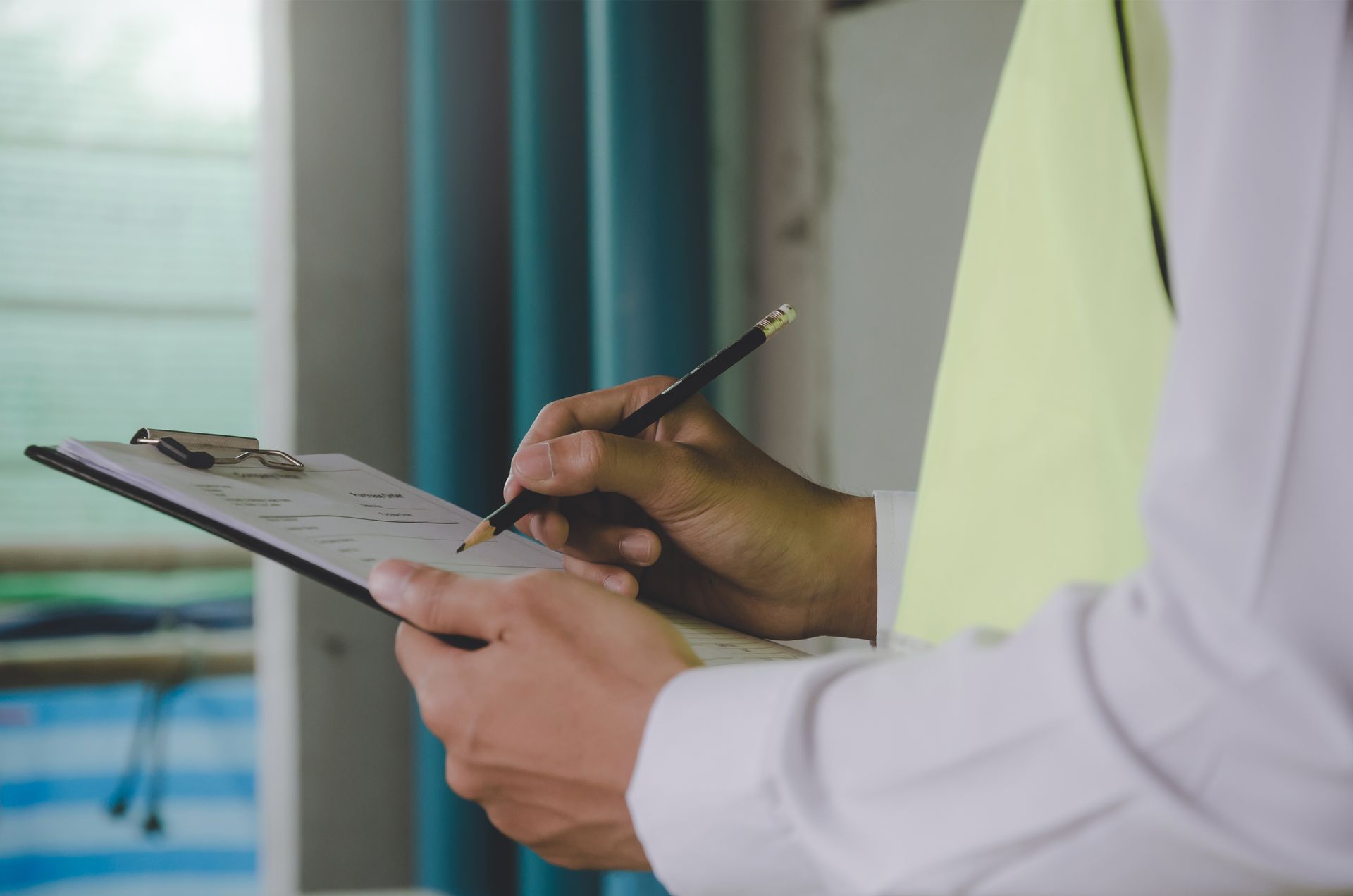 A Man is Writing on a Clipboard With a Pencil — All About Conveyancing Taree In Taree, NSW