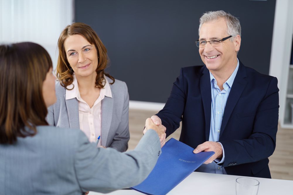 A Man and a Woman Are Shaking Hands During a Job Interview — All About Conveyancing Taree In Old Bar, NSW