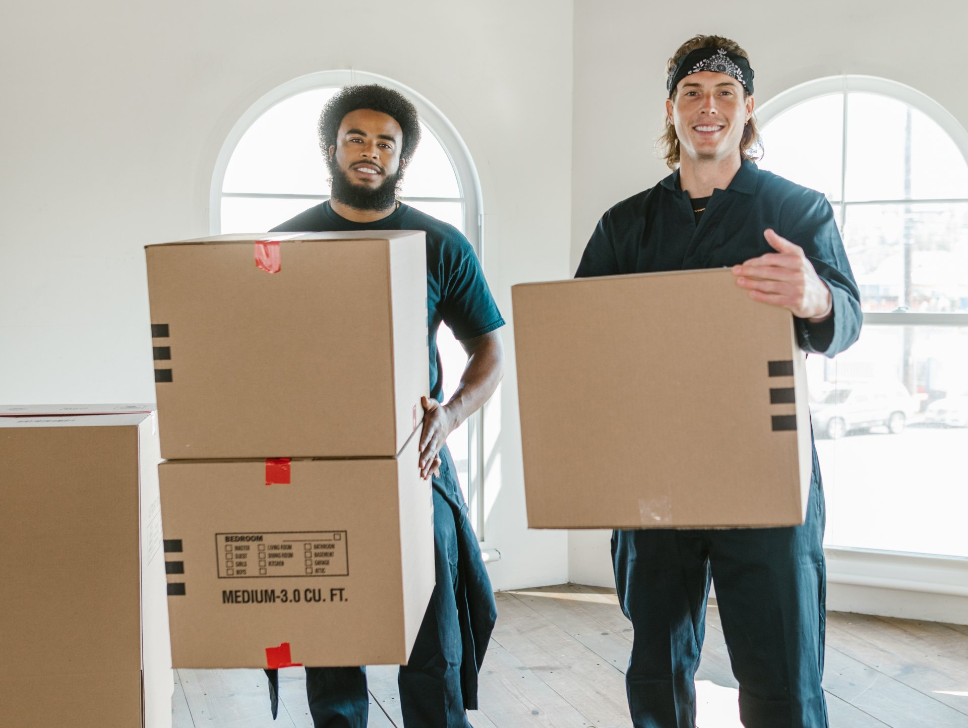 Two Men Are Carrying Cardboard Boxes in a Room — All About Conveyancing Taree In Taree, NSW