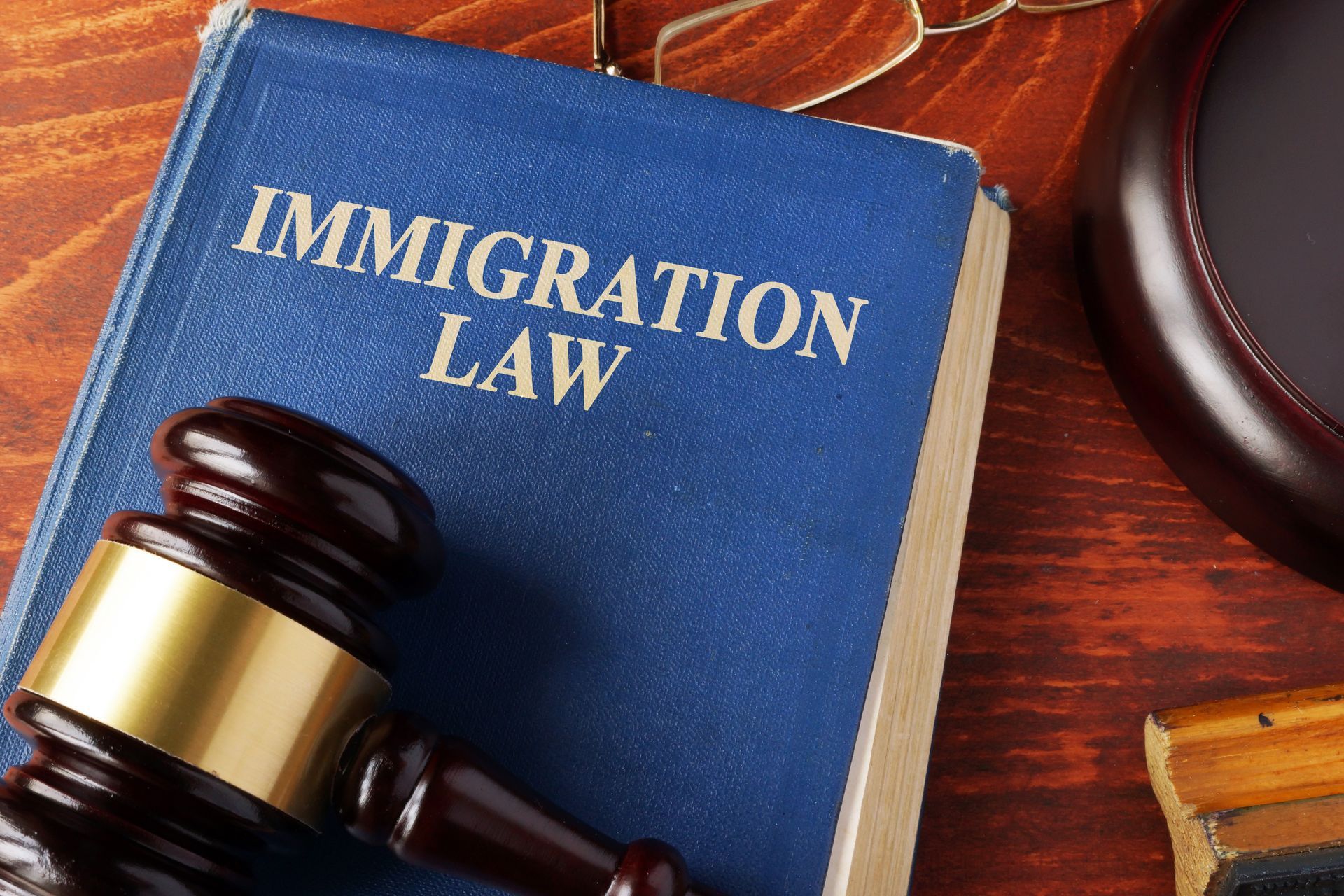 A blue book titled immigration law sits on a wooden table next to a judge's gavel.