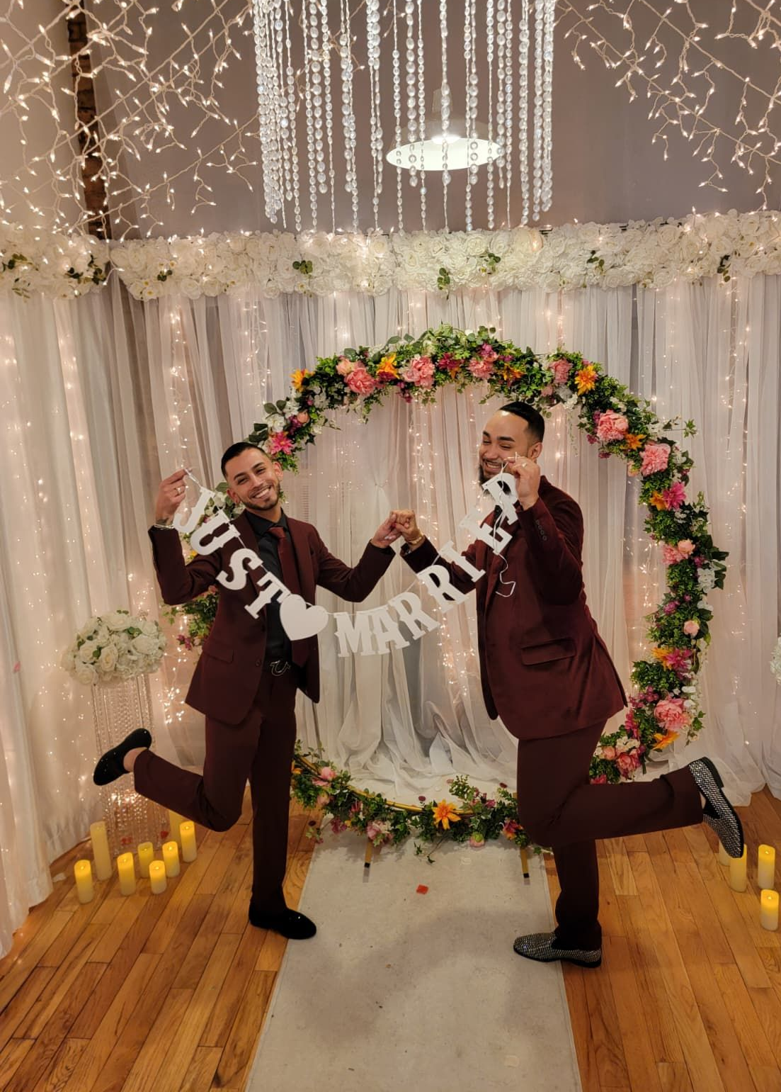 Two people in matching maroon suits hold a