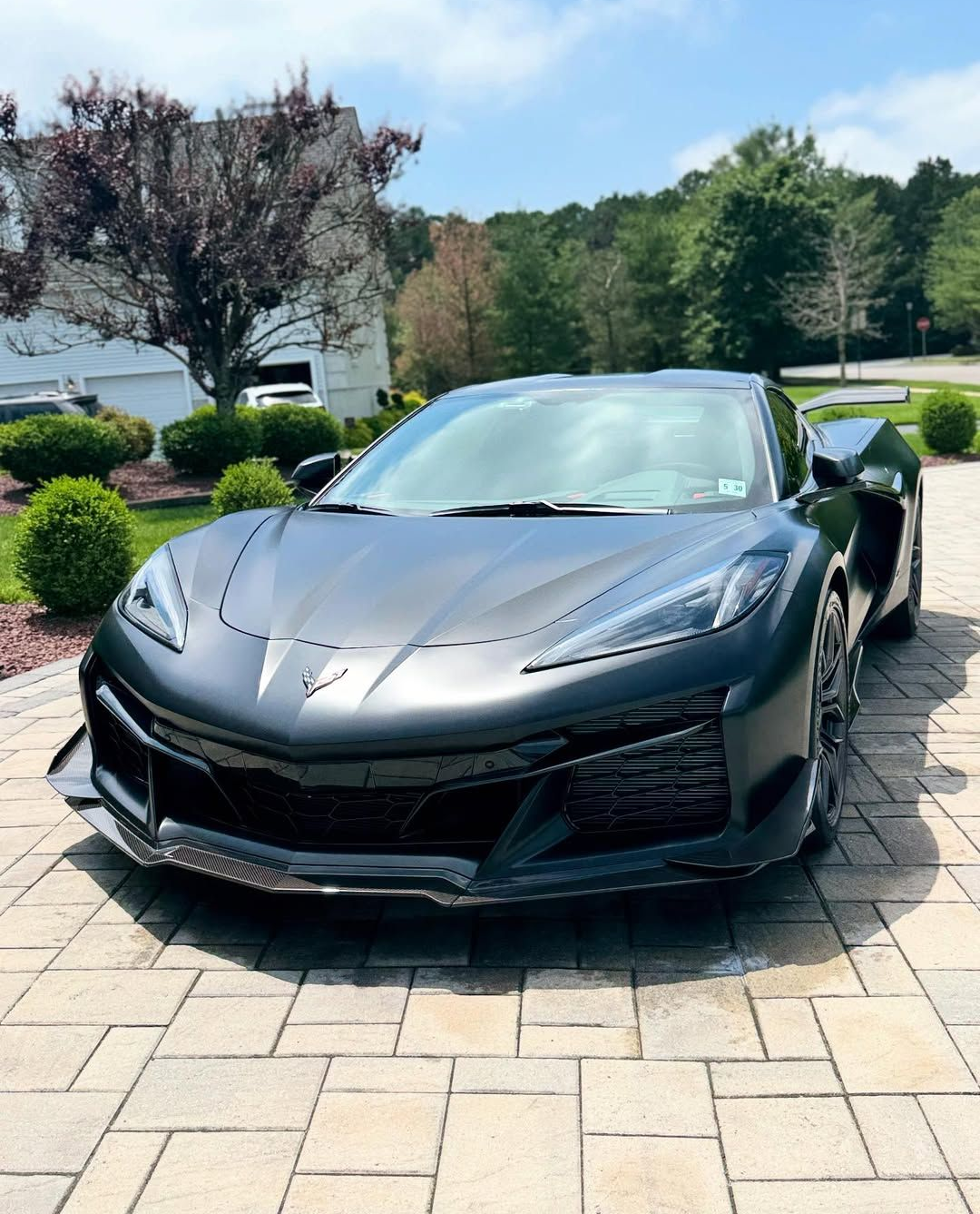 A large orange Mclaren 720s  is parked in front of a garage.