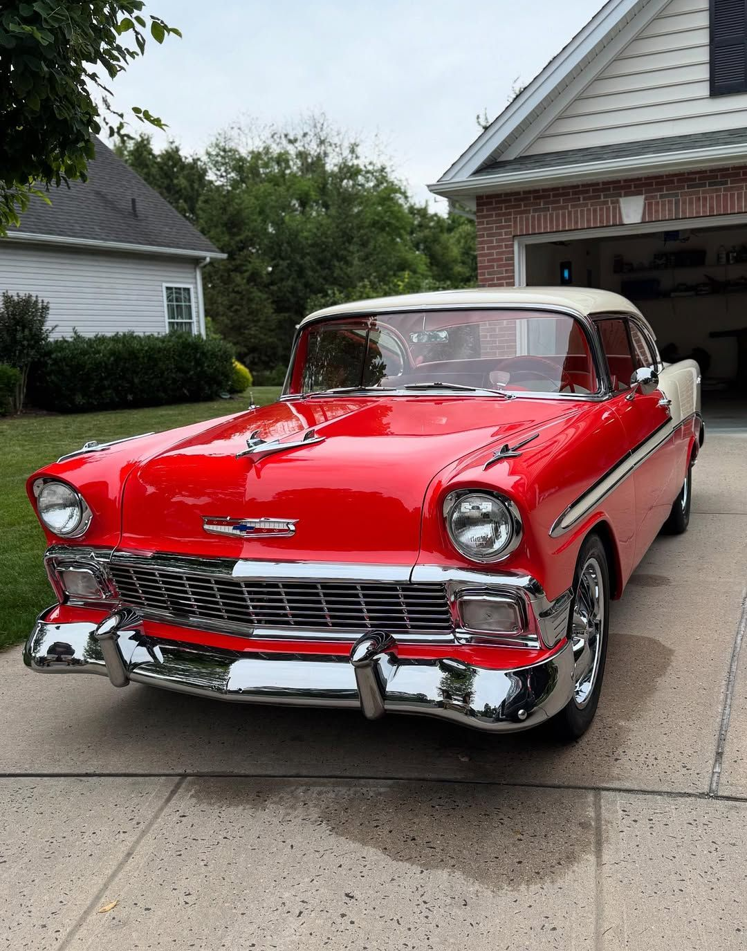 Red and white 1956 Chevrolet Bel Air classic car parked in front of a house.