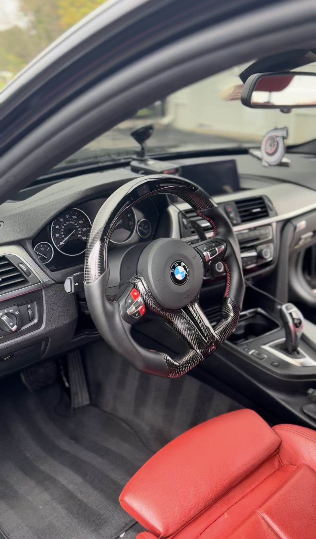 The inside of a bmw with a steering wheel and red seats.