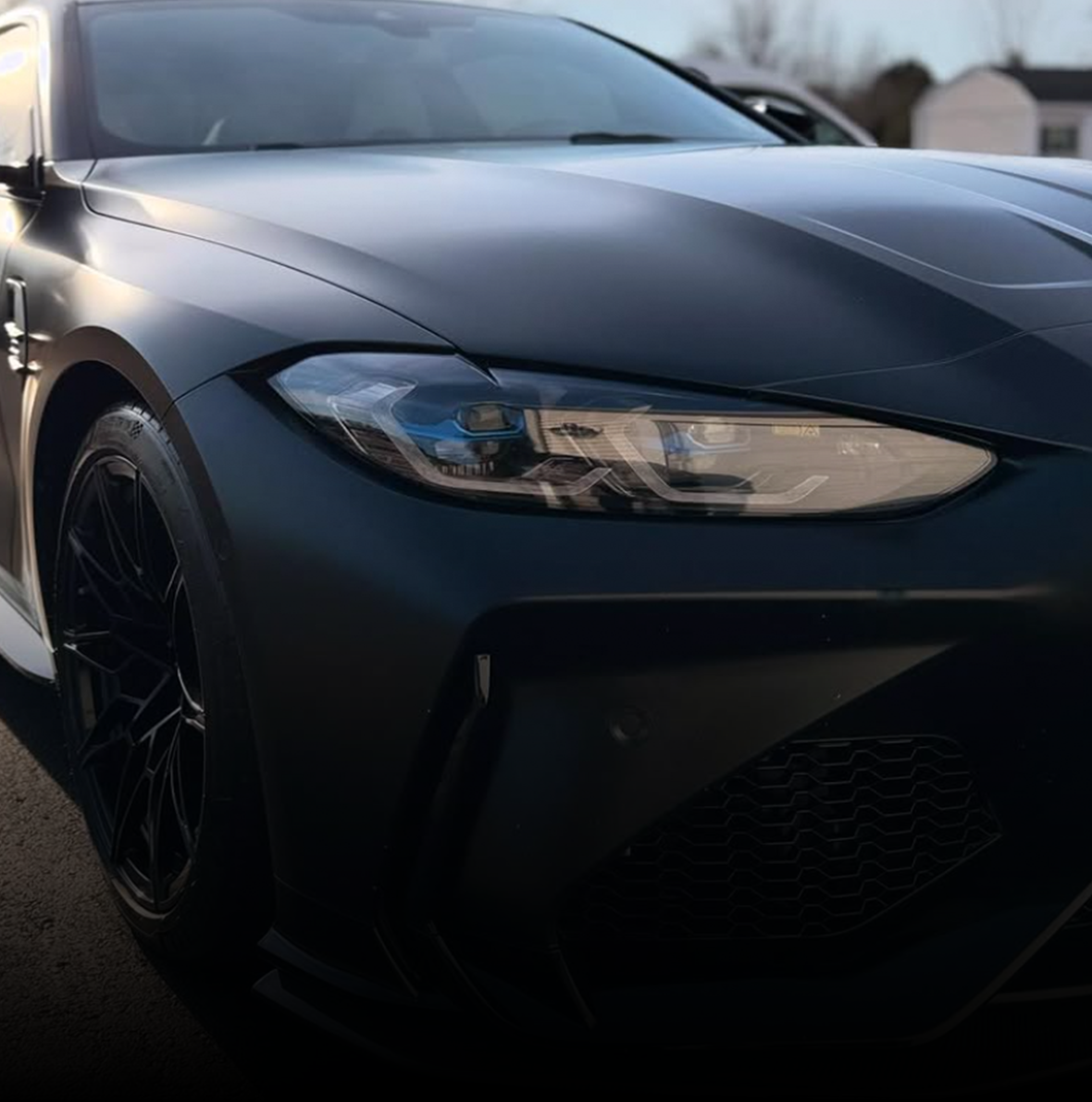 A close up of a black bmw's m4's headlight and hood.