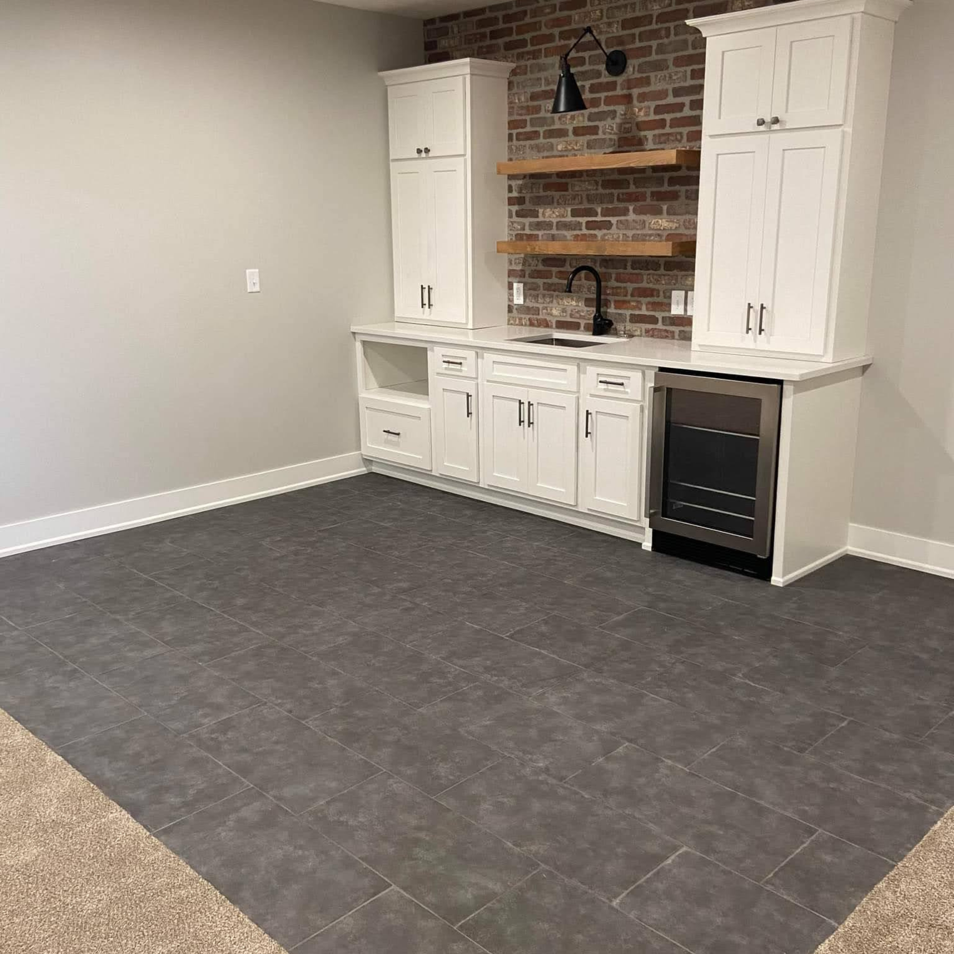 Empty room with gray tile floor and white built-in cabinets around a brick fireplace.