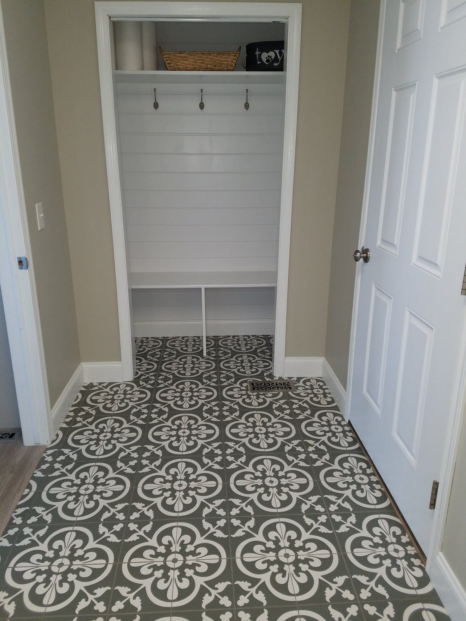 Gloved hands repairing large gray floor tiles near a drain grate