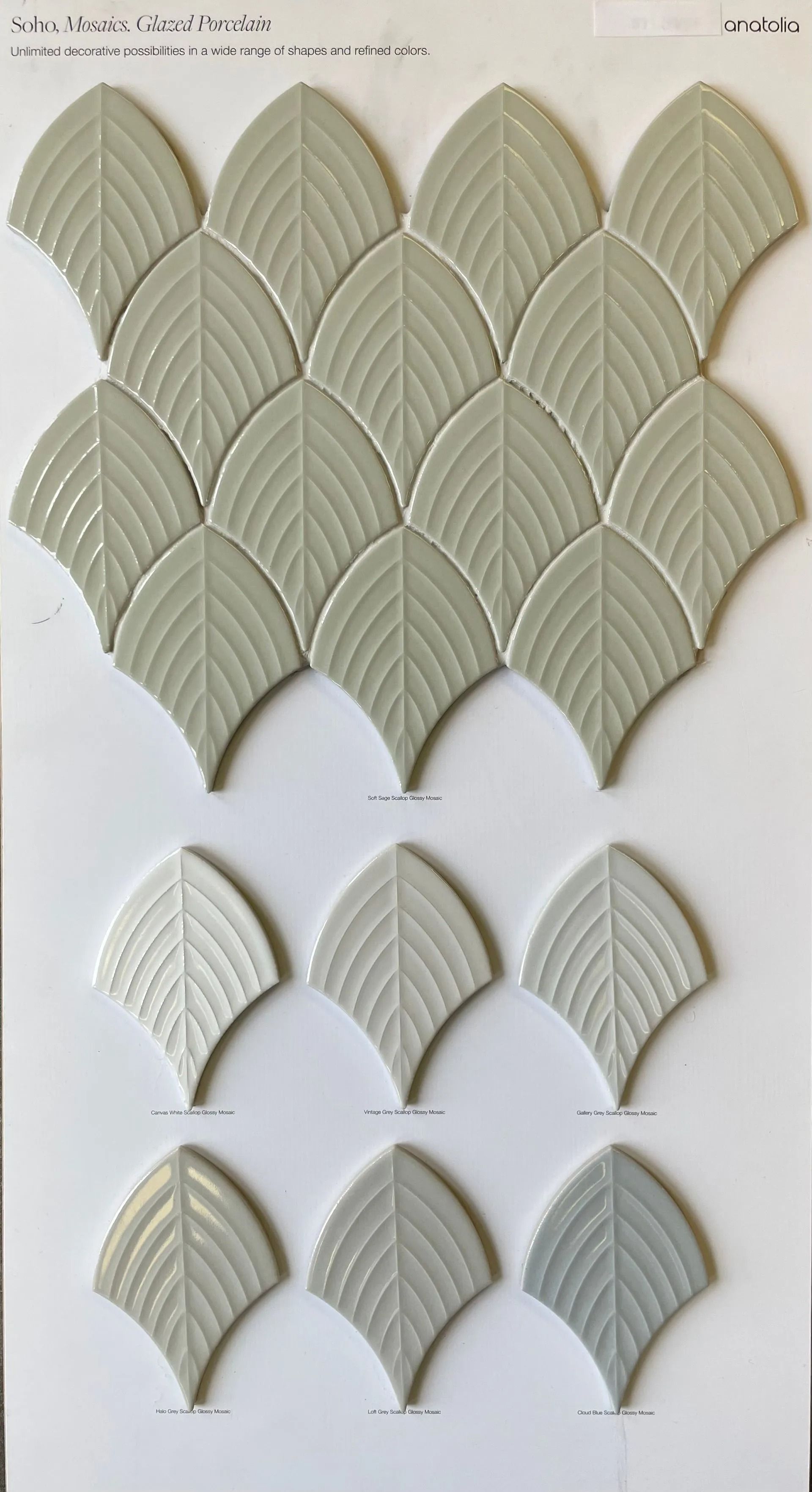 Leaf-shaped textured ceramic tiles in muted green and gray arranged on a white background
