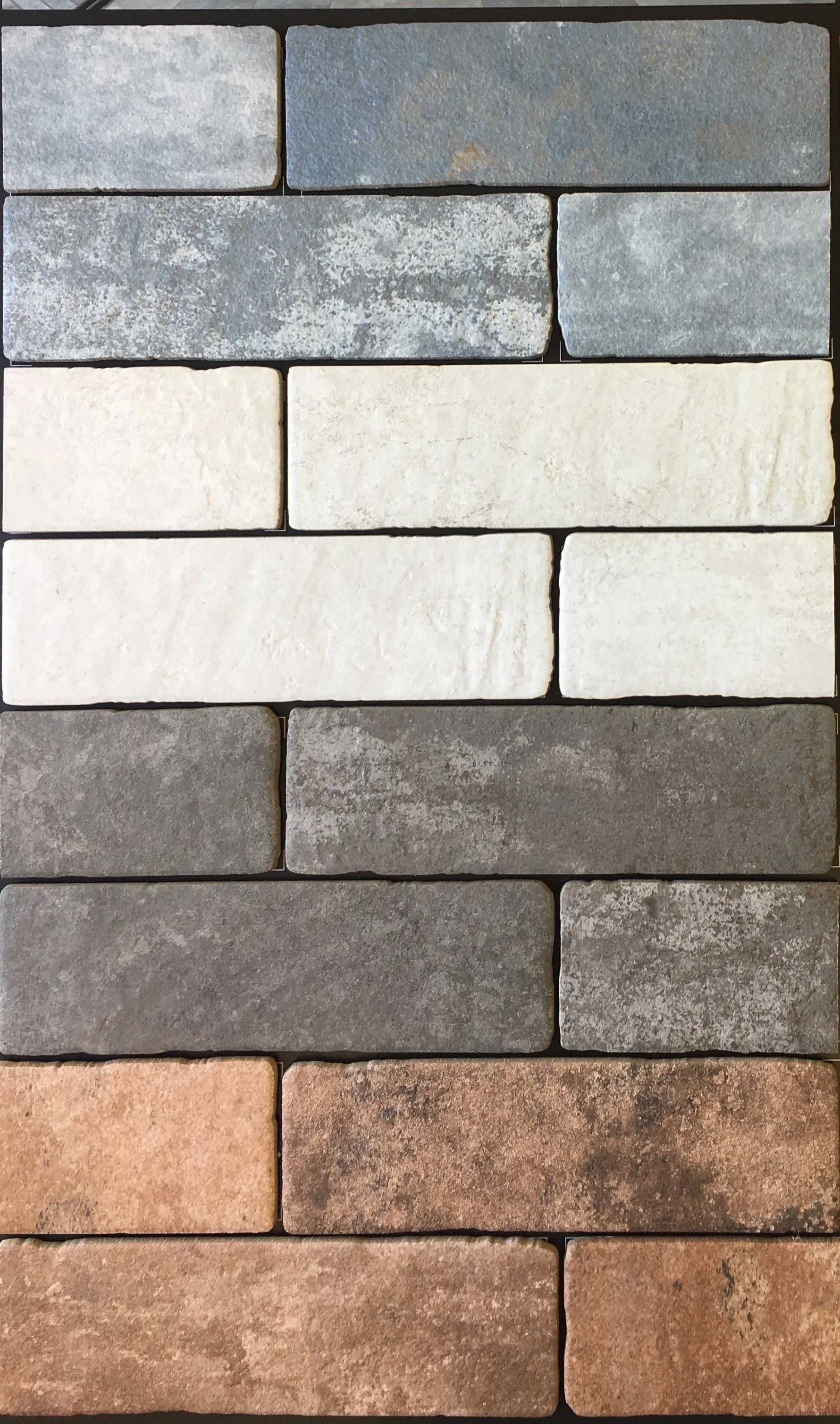 Stacked stone tile samples in gray, white, tan, and brown