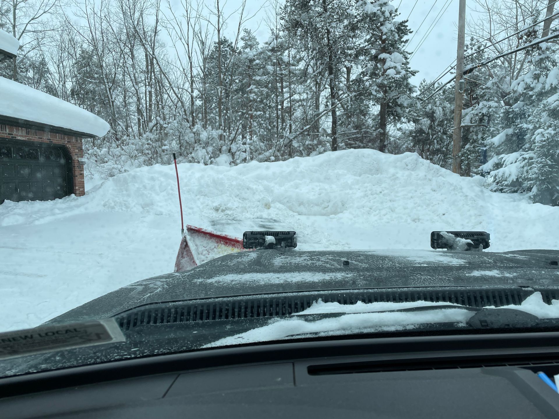 Snowplow pushing snow in front of a house on a snowy day.