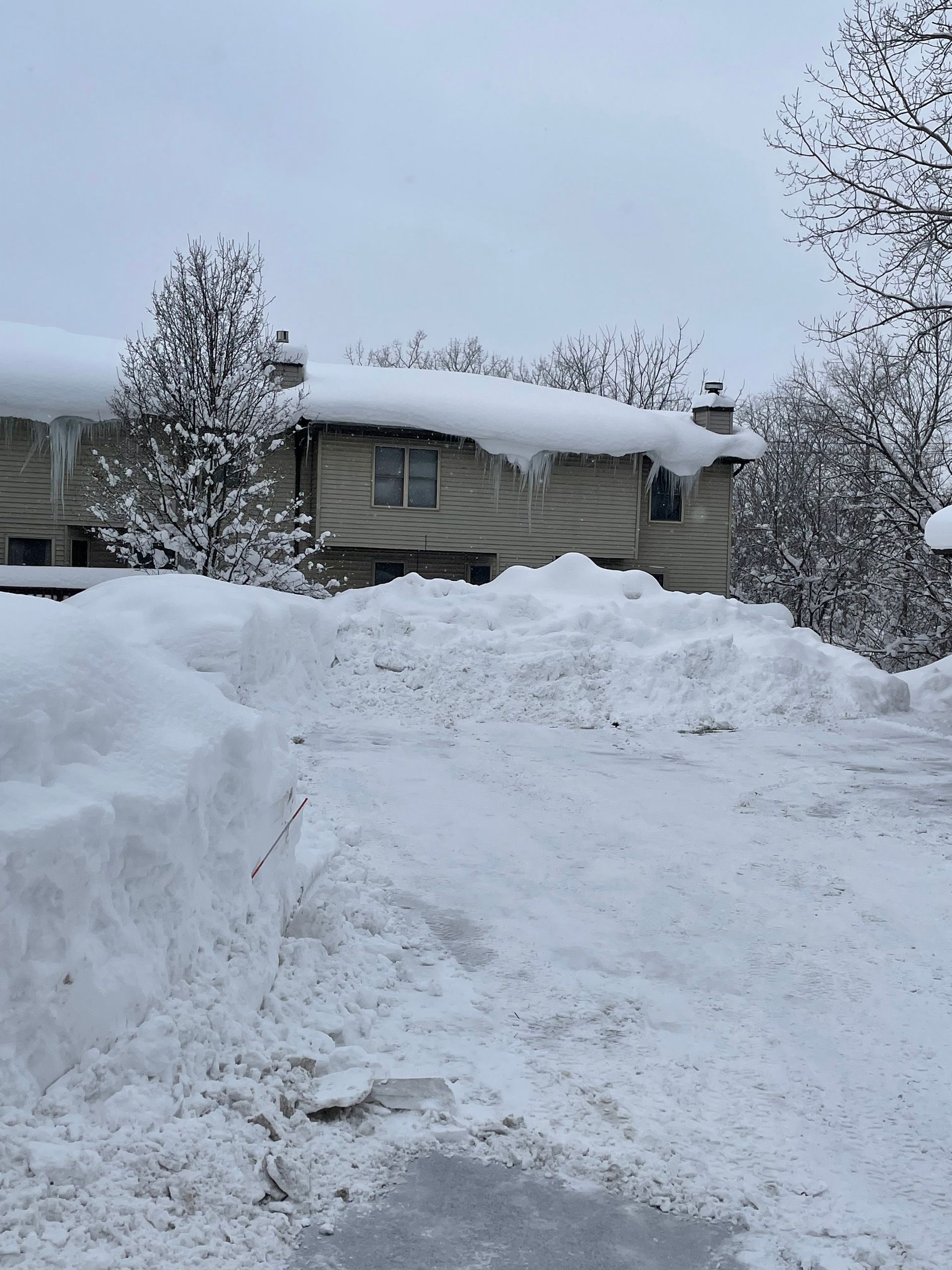Snow-covered townhouses with large snow drifts in the foreground; overcast sky.