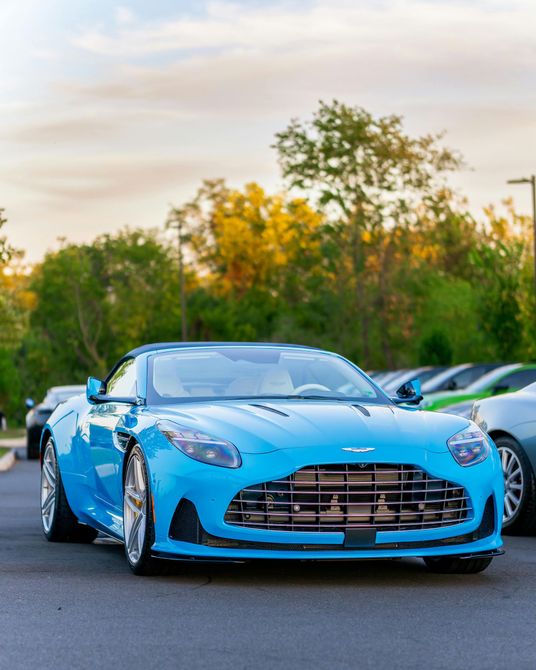 Blue Aston Martin DB11 sports car parked outdoors.