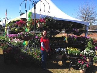 Woman is Standing in Front of a Tent Filled with Flowers – Mobile, AL – A Bloom Garden Center