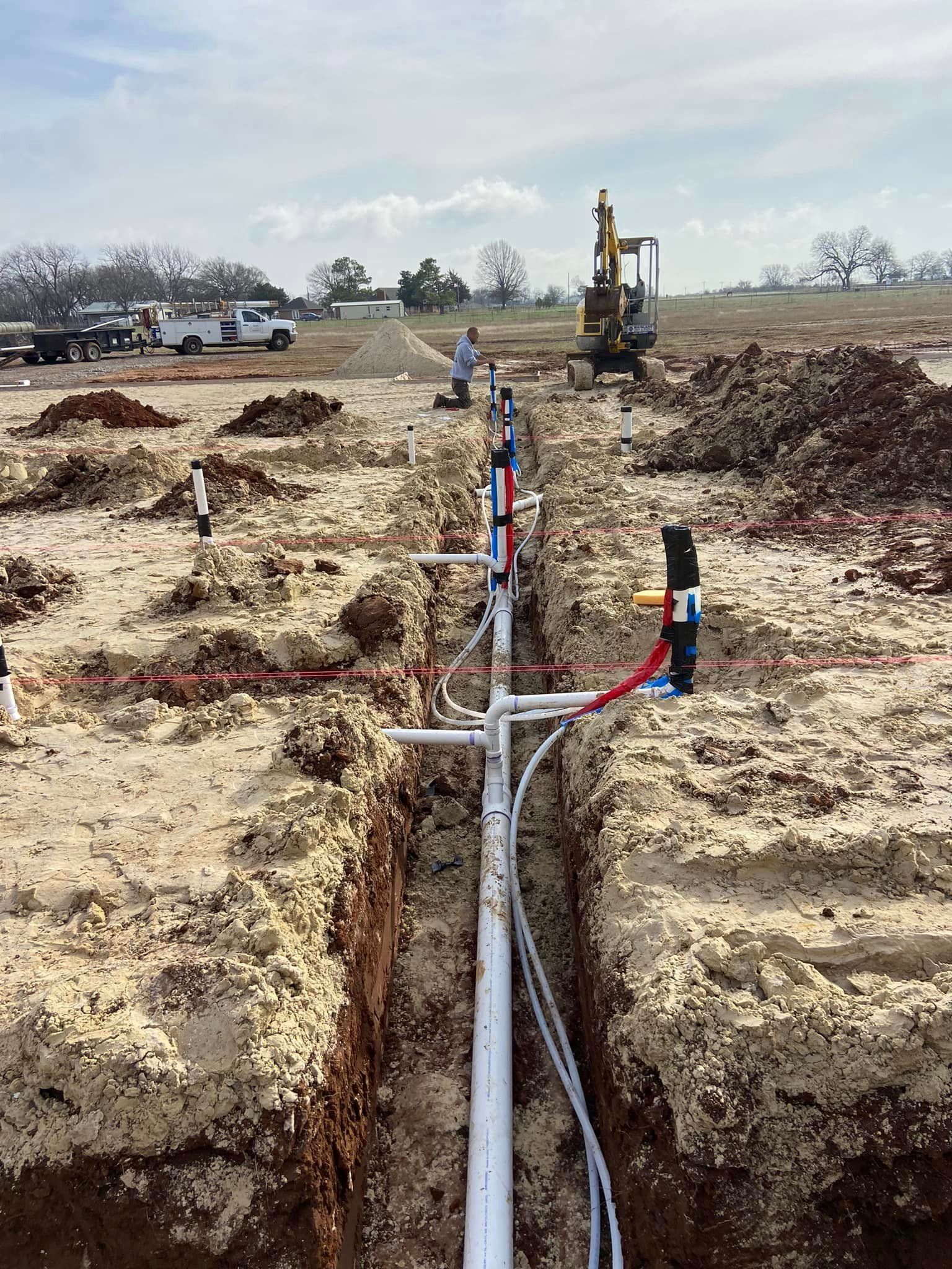 A Row of Pipes are being Installed in a Dirt Field — Pauls Valley, OK — Quality Plumbing Co.