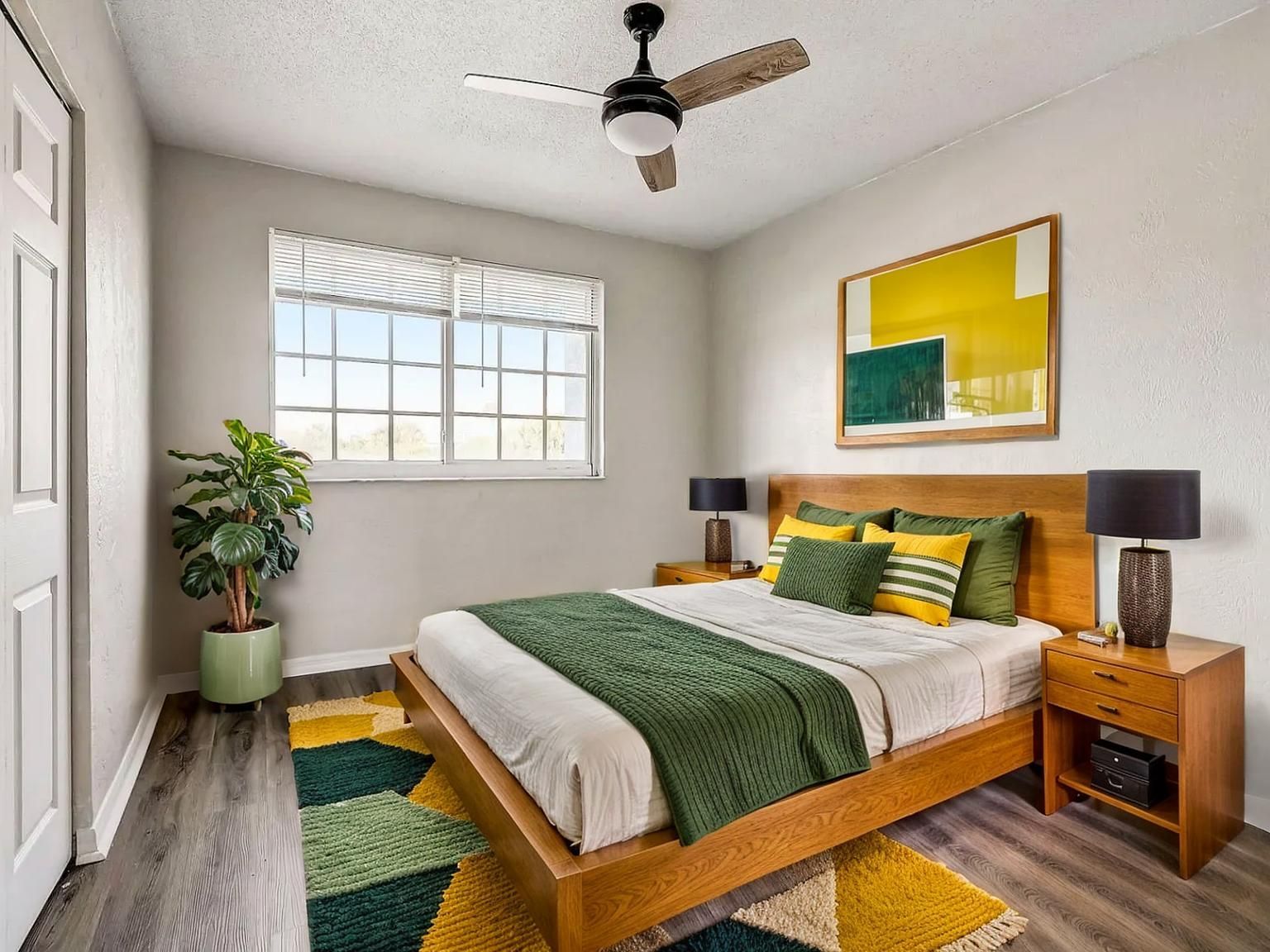 Modern bedroom with wooden bed, green accents, ceiling fan, window, and potted plant