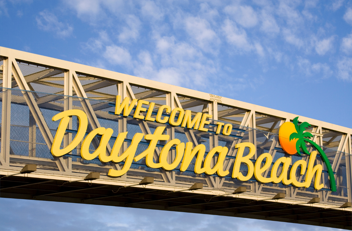 Welcome to Daytona Beach sign on a bridge against a blue sky