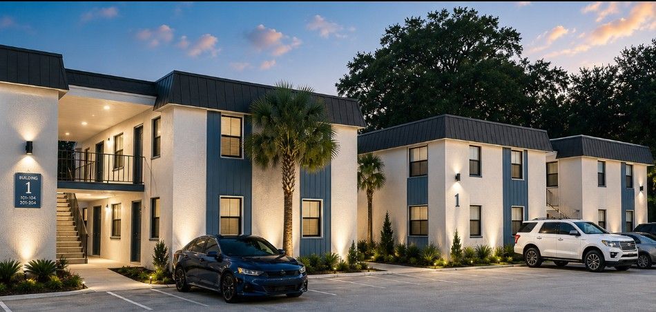 Modern apartment building exterior at dusk with parked cars and illuminated windows