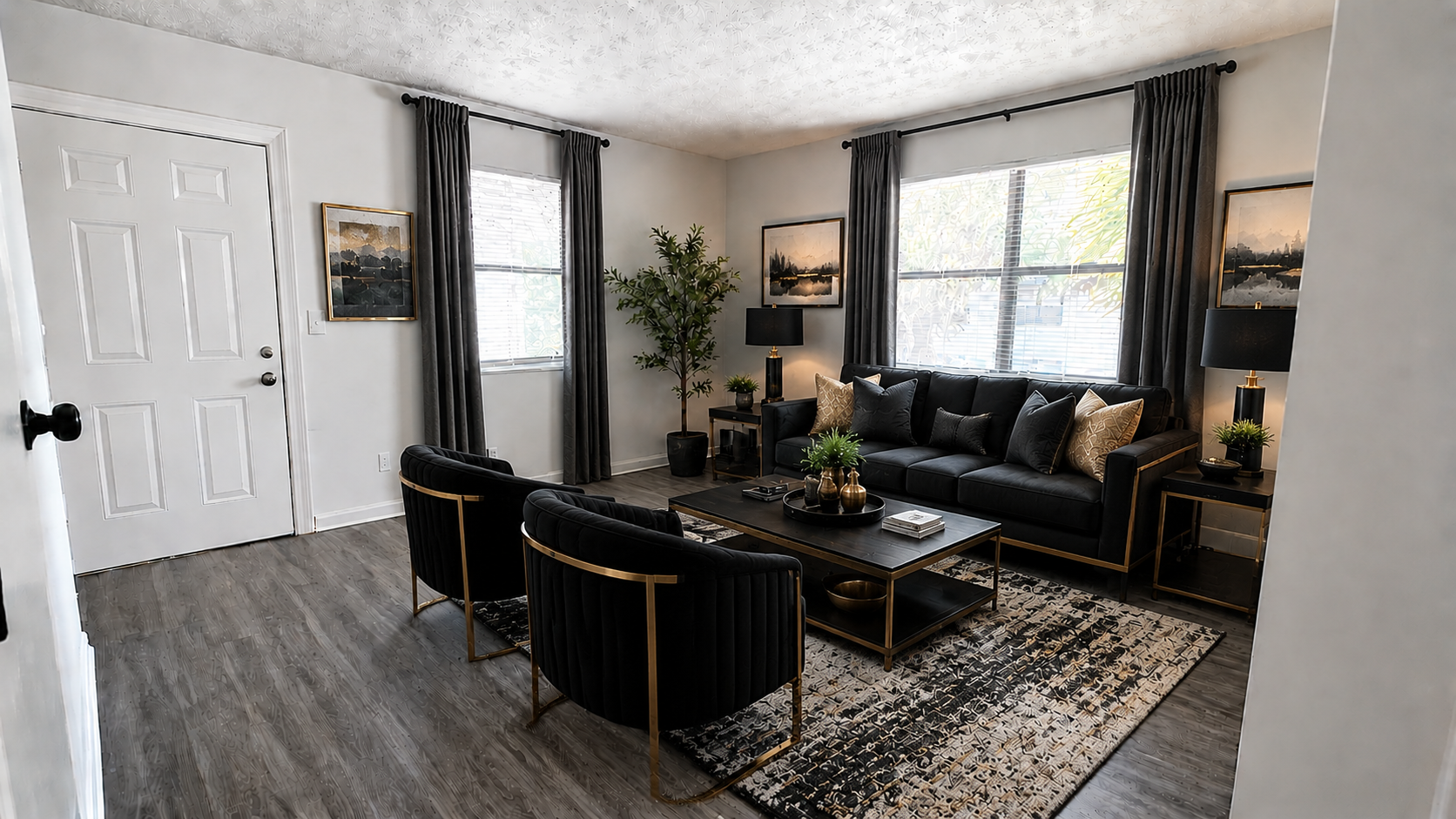 Stylish living room with black furniture, patterned rug, large windows, and gray wood flooring