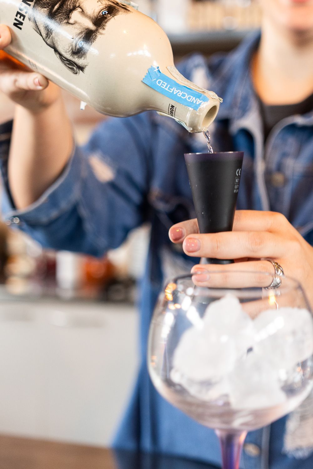 Una donna versa un drink in un bicchiere con ghiaccio.