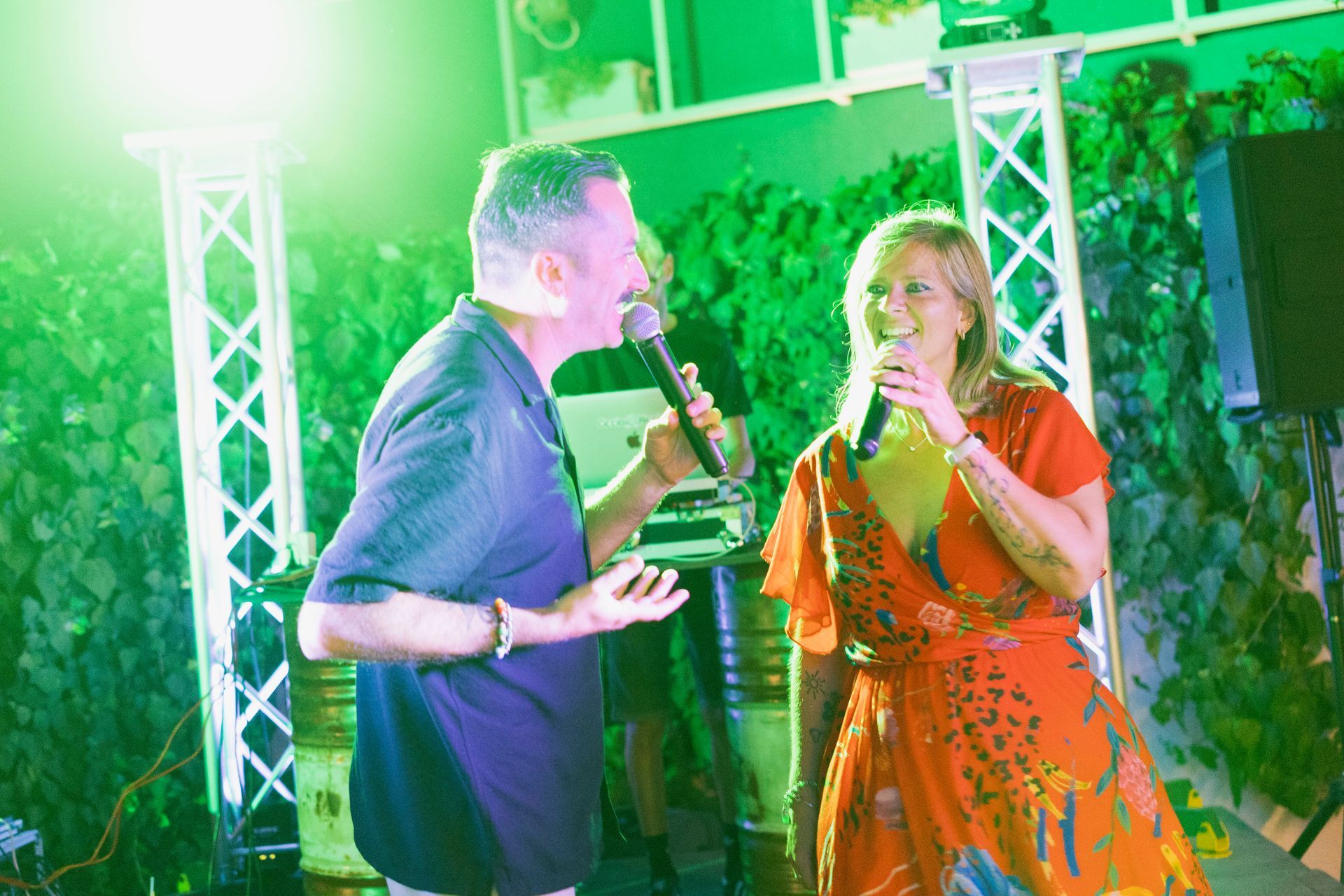 Un uomo e una donna cantano nei microfoni su un palco.