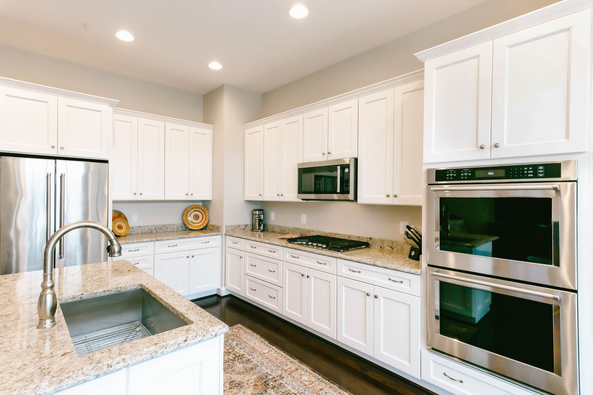 A kitchen with white cabinets , granite counter tops , stainless steel appliances and a sink.