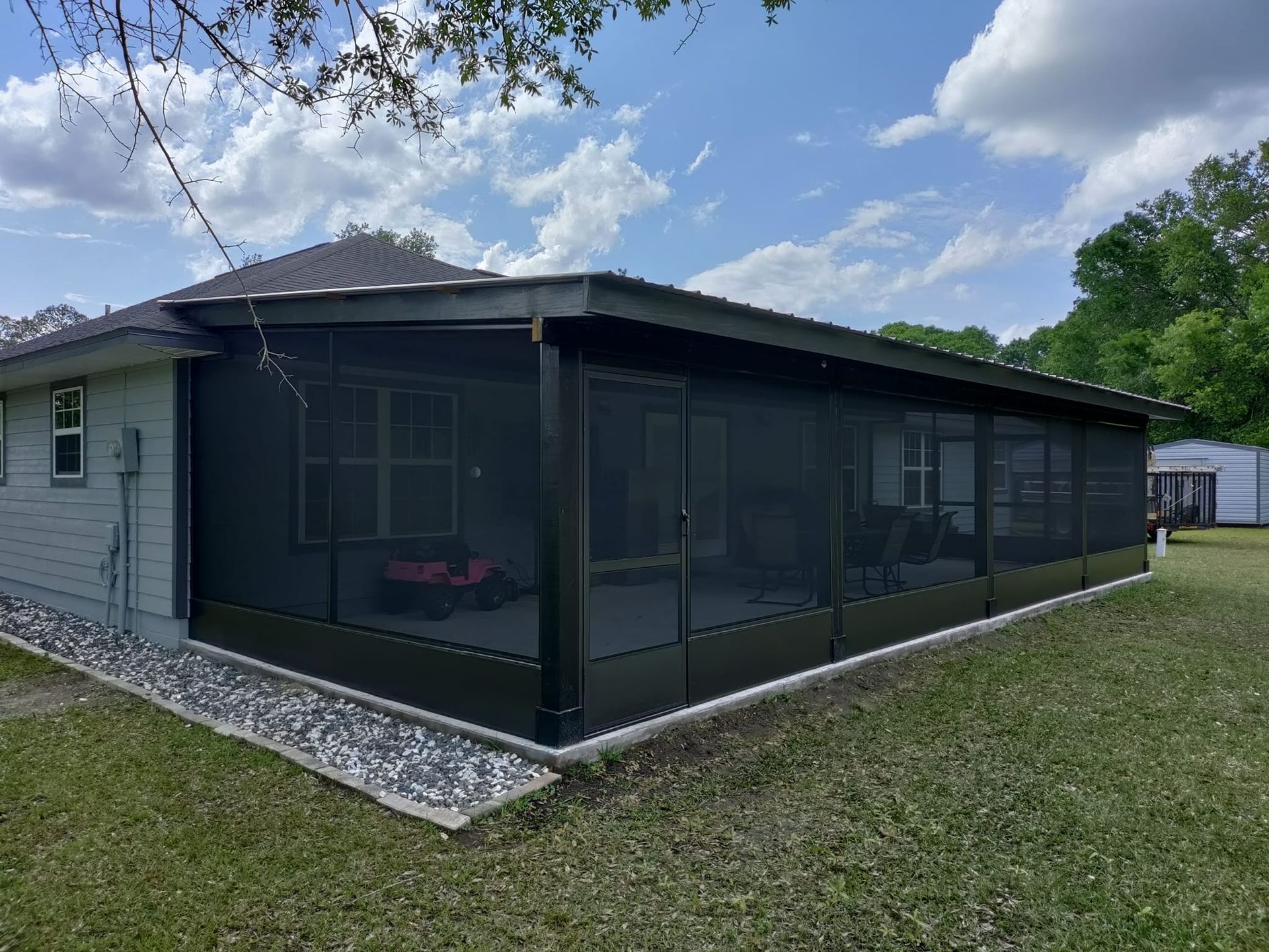 A house with a screened in porch in the backyard.