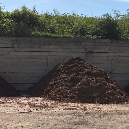 Pile of dirt beside a concrete wall under bright sunlight
