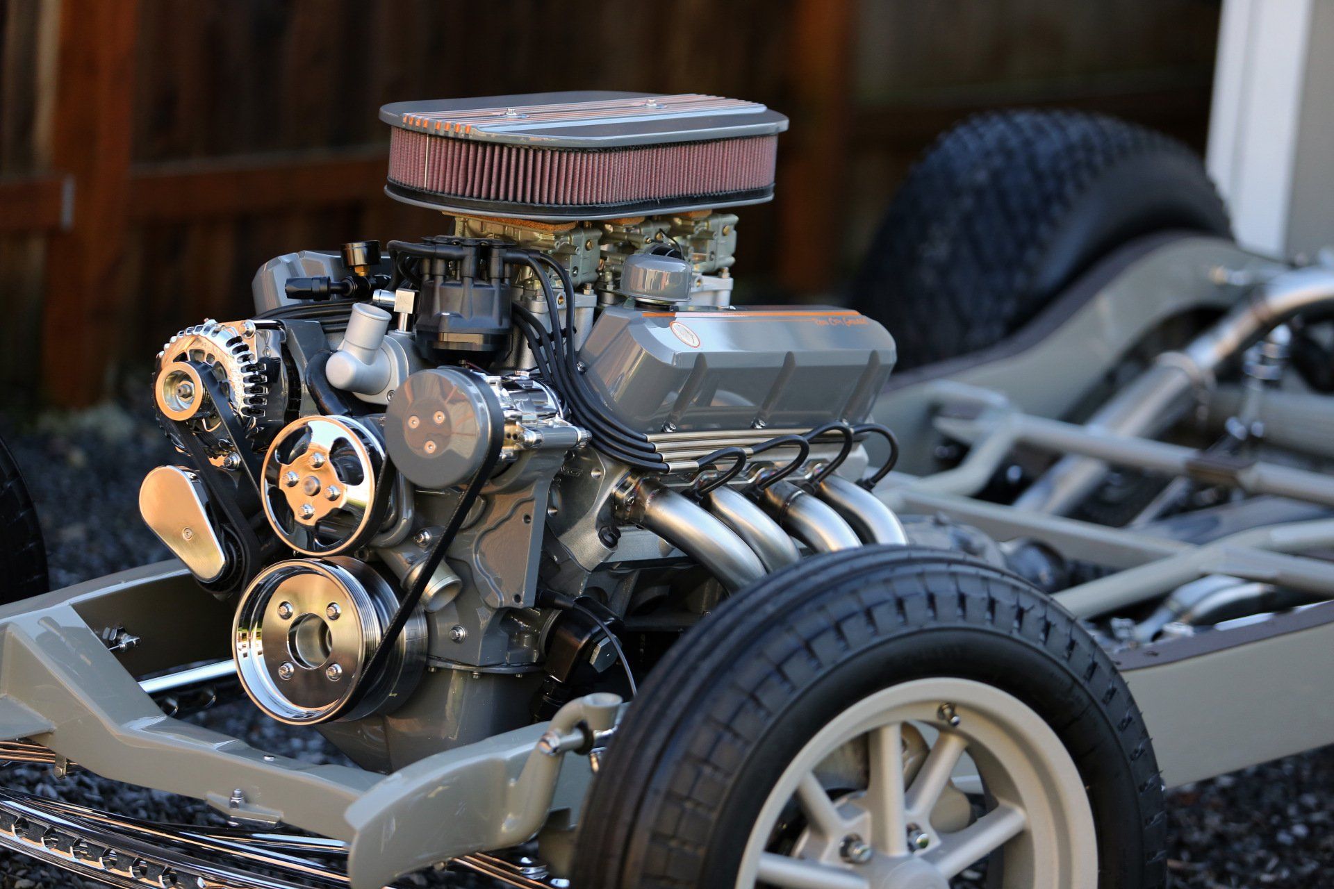 Close-up of a polished car engine with exposed chrome parts and a round air filter on a custom chassis