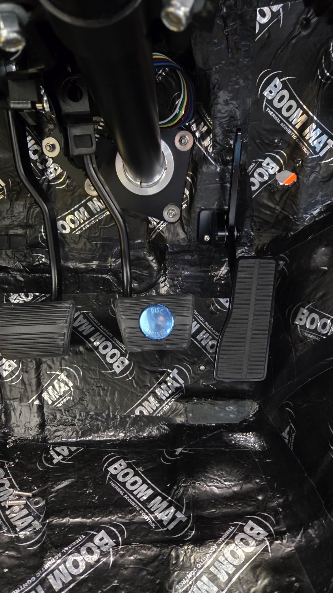 Black motorcycle components with a blue cap and bolts, close-up of a mechanical assembly