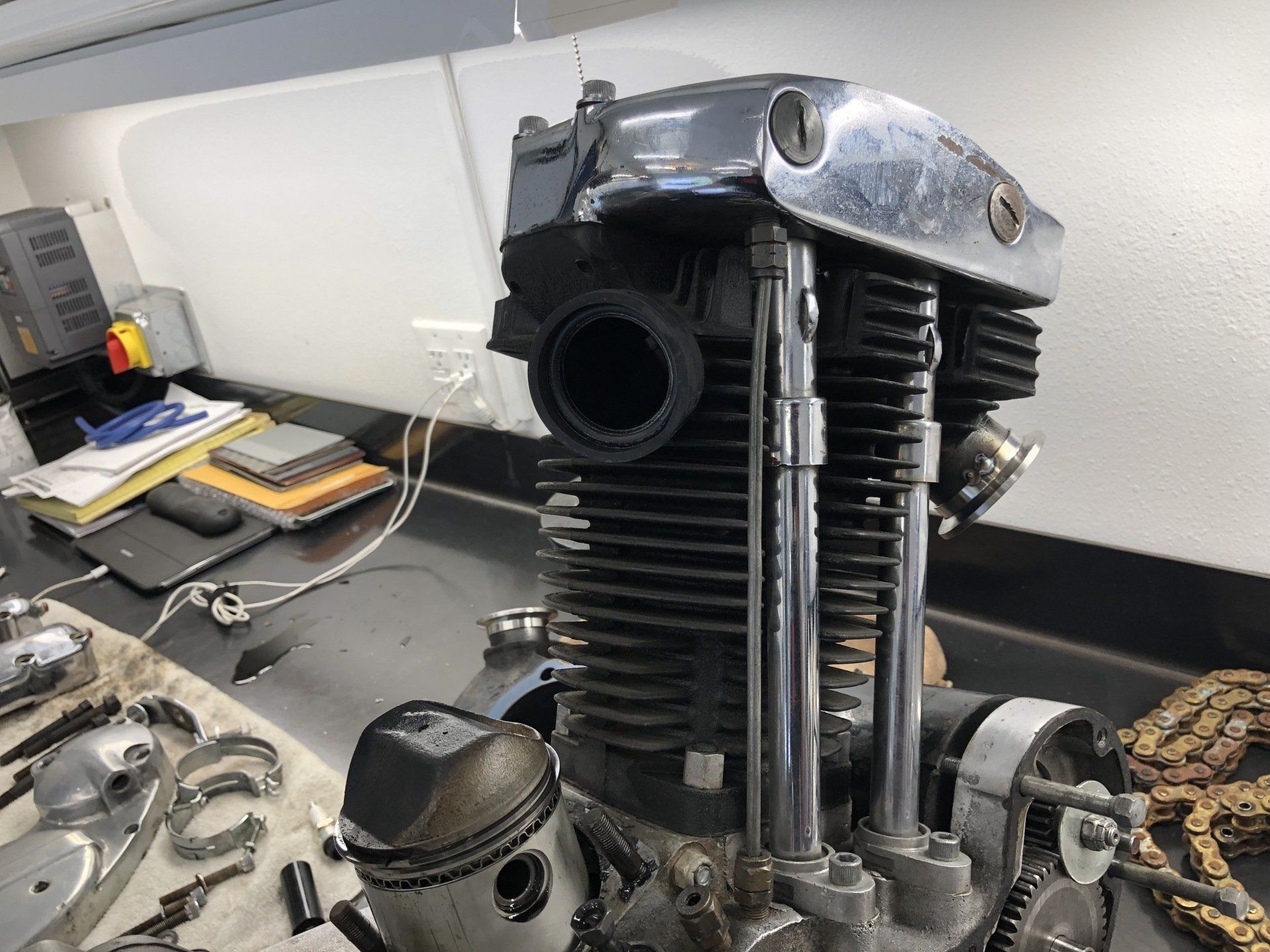 Vintage motorcycle engine on a workbench with tools and parts in a workshop