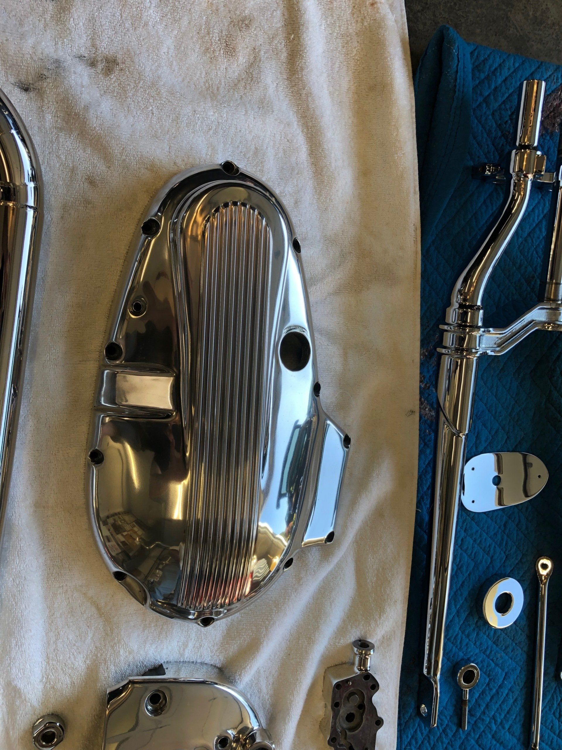 Chrome car parts laid on a white towel, including a grille, trim, and blue backing piece
