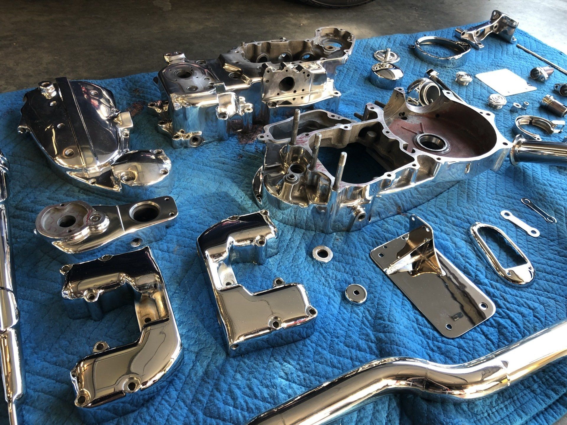 Assorted chrome metal parts arranged on a blue towel on a workbench