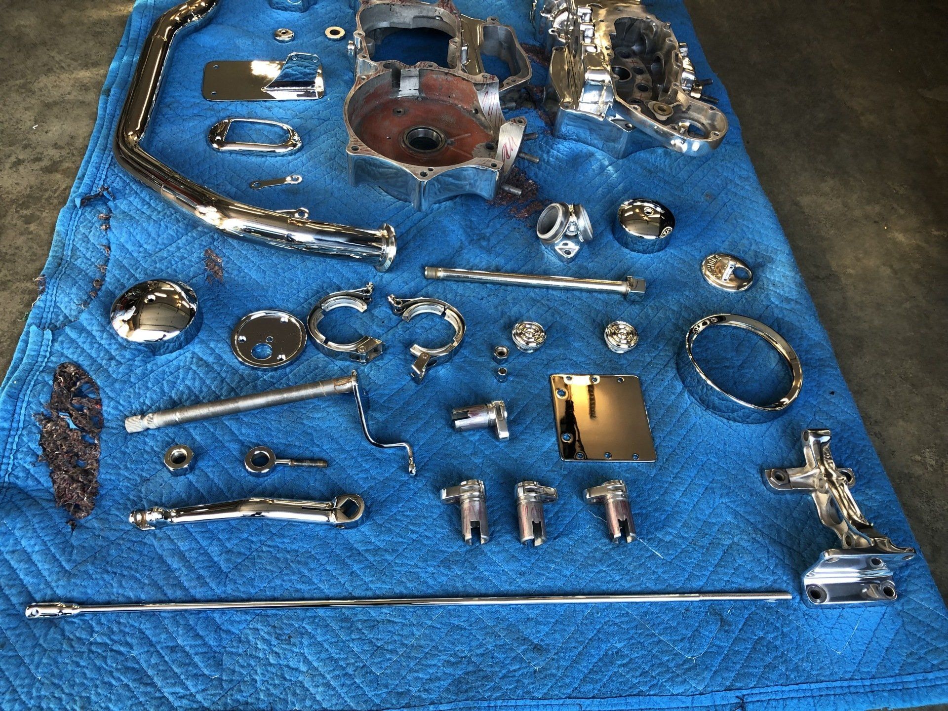Blue workshop mat with assorted metal parts and tools laid out on it