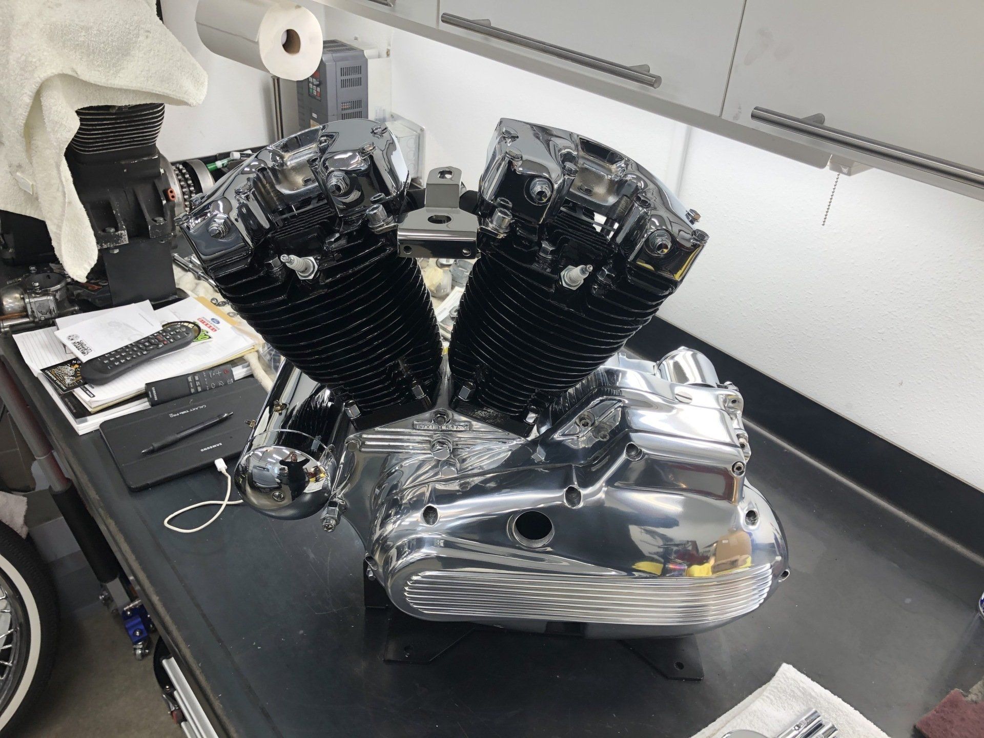 Polished black V-twin motorcycle engine mounted on a workbench in a garage