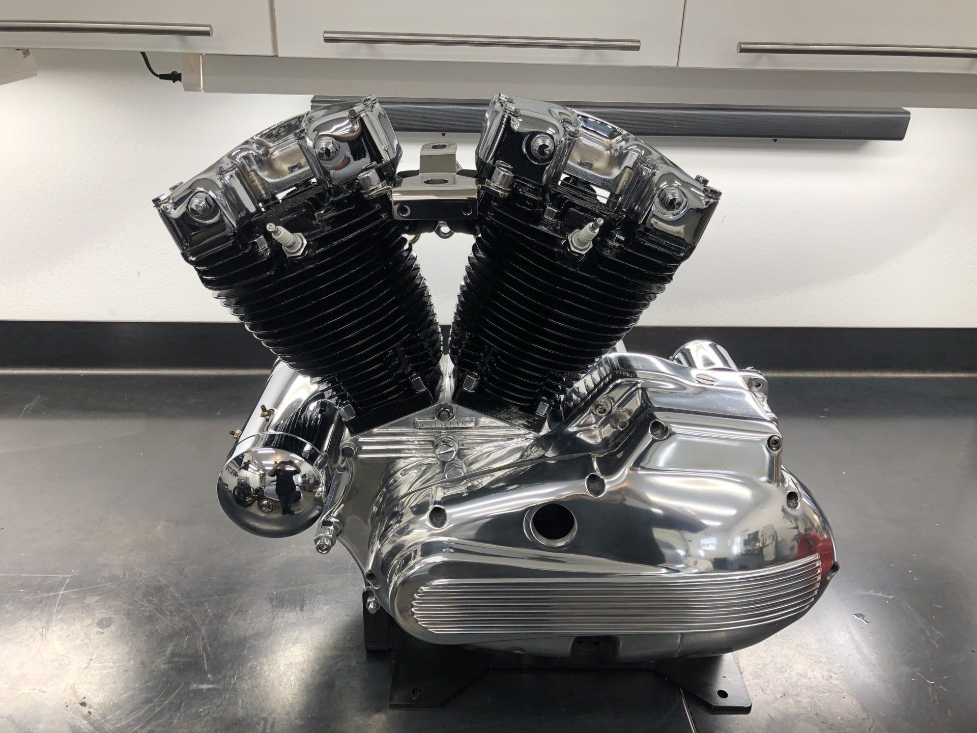 Chrome V-twin engine on a workbench in a shop, with shiny polished covers and black cylinder fins.