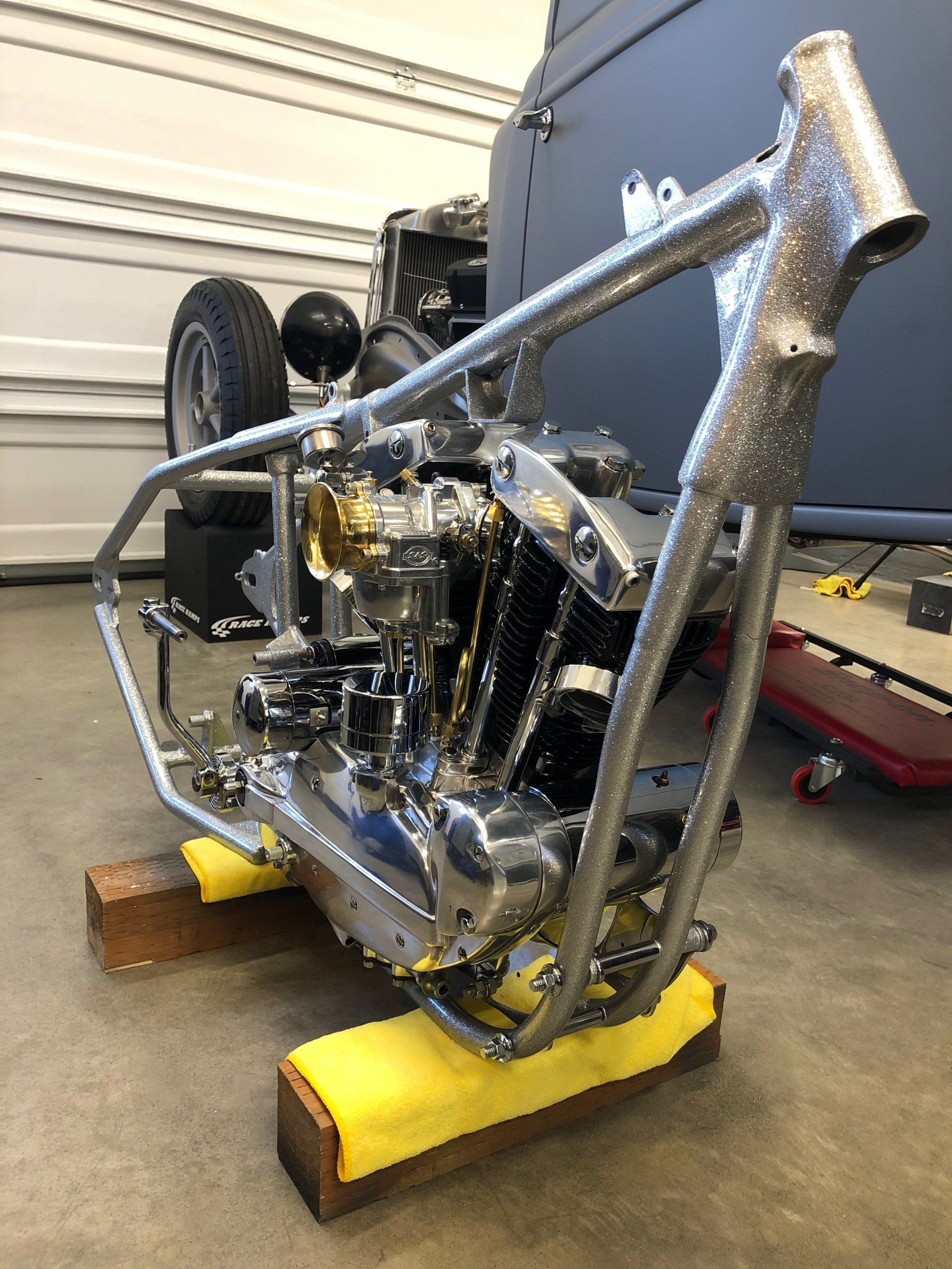 Shiny motorcycle engine and frame mounted on yellow stands in a garage/workshop