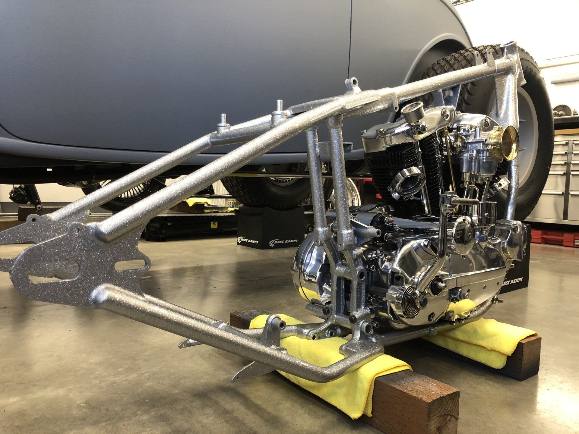 Motorcycle engine and frame mounted on a yellow stand in a workshop